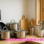 木製のキッチンカウンターの上に、フライパンスタンドに立てられた黒いフライパン、複数のステンレス鍋、まな板、調理器具を入れたスタンドなどが整然と並んでいる。右下に「立てる収納で快適キッチン」というピンク色の文字が入っている。